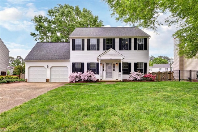 colonial-style house featuring a front lawn, fence, driveway, and a garage