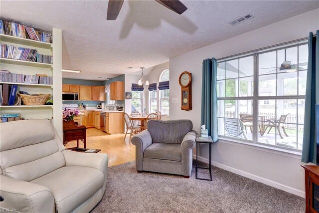 living room featuring baseboards, a ceiling fan, visible vents, and a textured ceiling