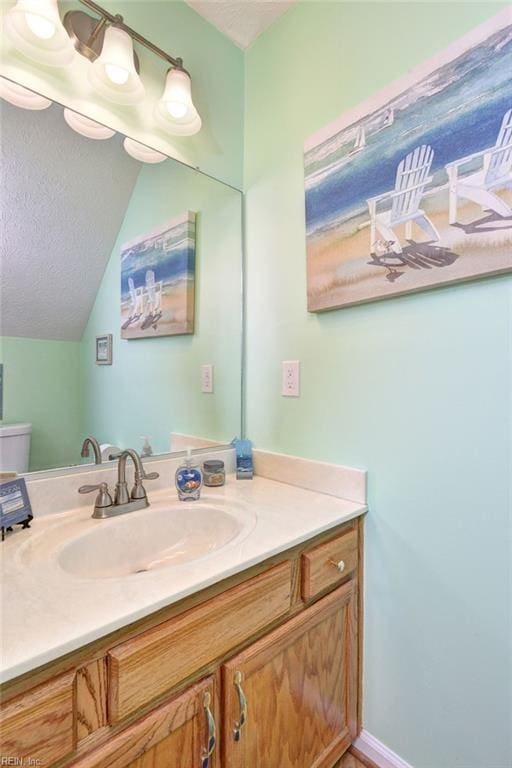 half bathroom featuring lofted ceiling, vanity, a textured ceiling, and toilet