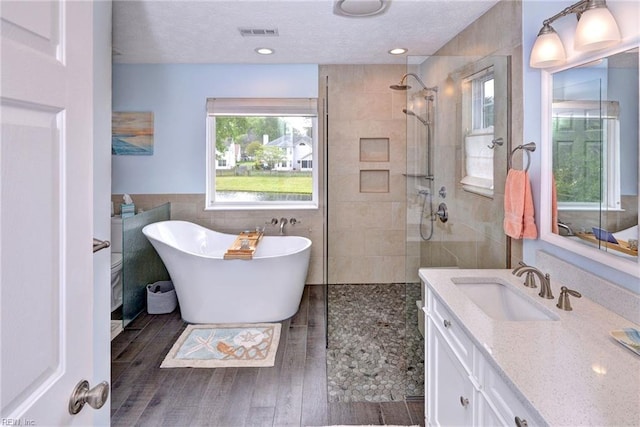 bathroom featuring a freestanding bath, tile walls, visible vents, walk in shower, and wood finished floors