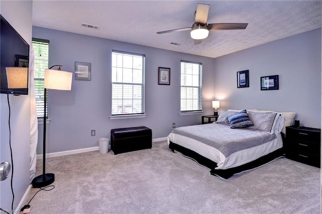 bedroom with a textured ceiling, visible vents, carpet flooring, and baseboards