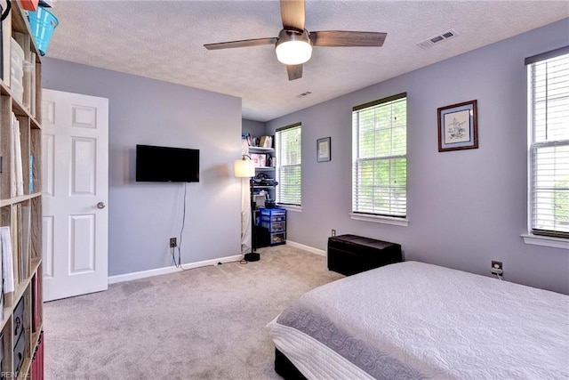 carpeted bedroom featuring baseboards, multiple windows, visible vents, and a textured ceiling