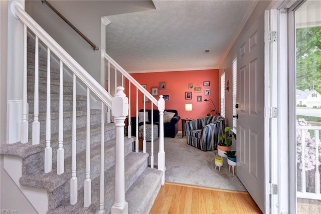 foyer with stairway, ornamental molding, wood finished floors, and a textured ceiling