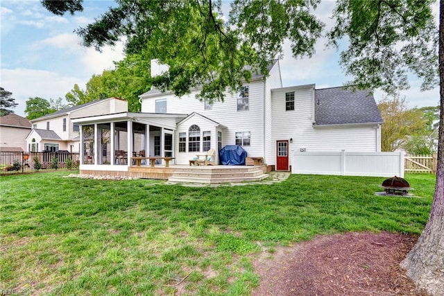 back of house with a fenced backyard, a fire pit, a sunroom, and a yard