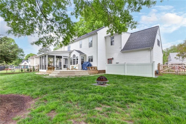 back of house featuring a fenced backyard, an outdoor fire pit, a sunroom, and a yard