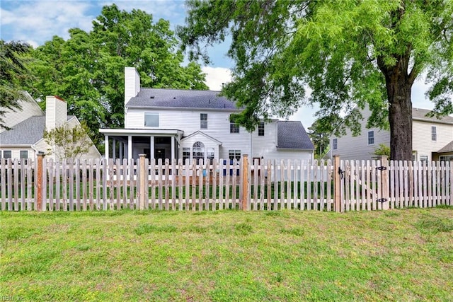 back of property featuring a fenced backyard, a chimney, a shingled roof, a yard, and a sunroom