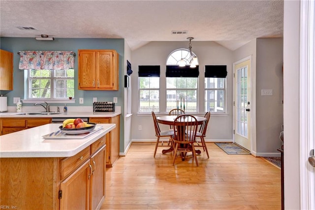 kitchen featuring light wood finished floors, a sink, a textured ceiling, visible vents, and light countertops