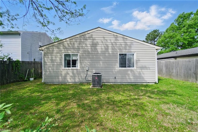 back of house with a fenced backyard, cooling unit, and a lawn