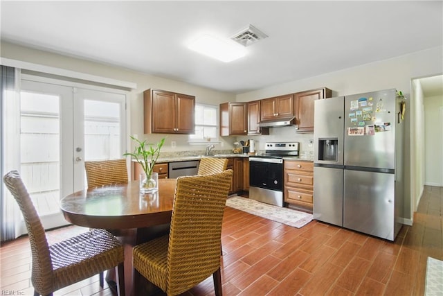kitchen featuring under cabinet range hood, visible vents, light countertops, appliances with stainless steel finishes, and dark wood finished floors