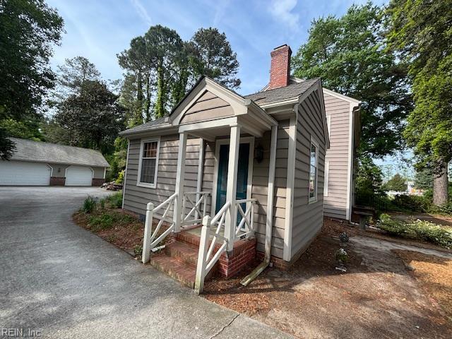 26060 Court St, Courtland, VA 23837 - bungalow featuring a chimney, an outdoor structure, and a garage