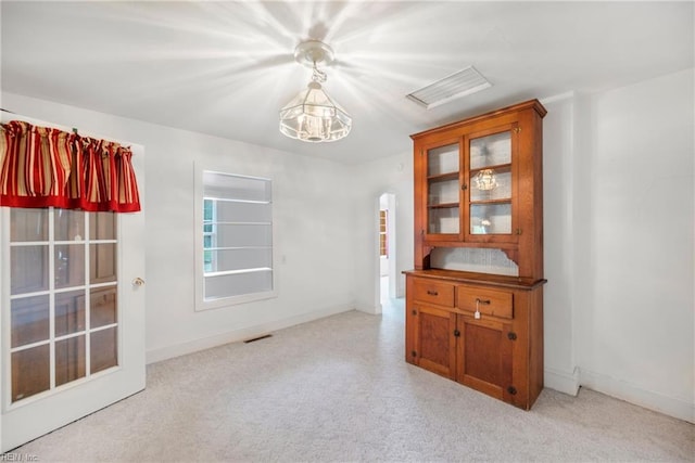 spare room with light colored carpet, arched walkways, baseboards, and visible vents