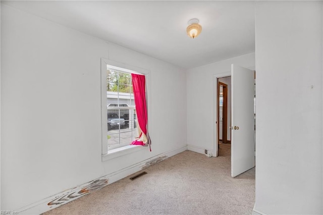 spare room featuring light carpet and visible vents
