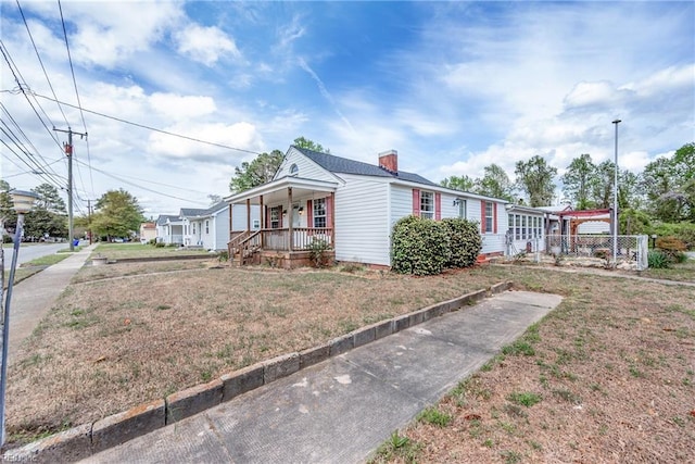 view of front of property with a porch, a chimney, and a front yard
