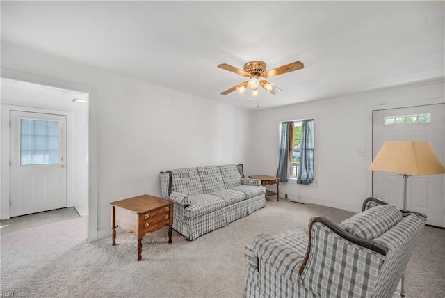 living area with carpet flooring, baseboards, and a ceiling fan