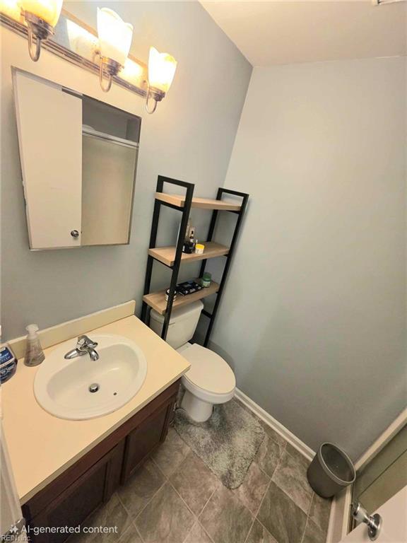 bathroom with baseboards, toilet, and vanity
