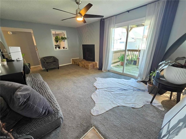 carpeted living room featuring a fireplace, a textured ceiling, a ceiling fan, and baseboards