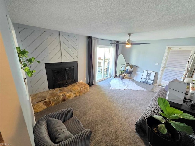 living area featuring a large fireplace, carpet, a textured ceiling, and ceiling fan