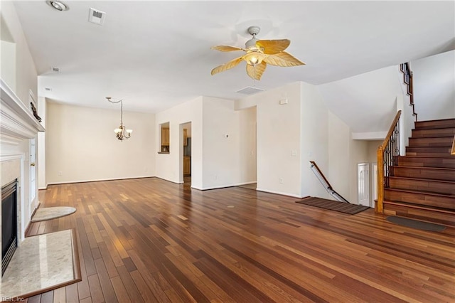 unfurnished living room featuring stairs, hardwood / wood-style floors, ceiling fan with notable chandelier, a high end fireplace, and visible vents