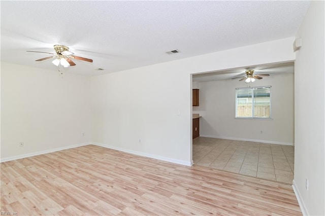unfurnished room with baseboards, visible vents, light wood-style floors, and ceiling fan
