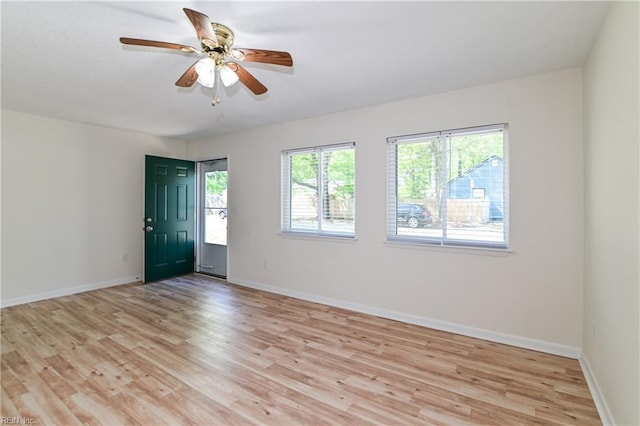 empty room featuring ceiling fan, baseboards, and light wood finished floors