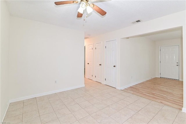 unfurnished room with baseboards, a ceiling fan, visible vents, and light tile patterned floors