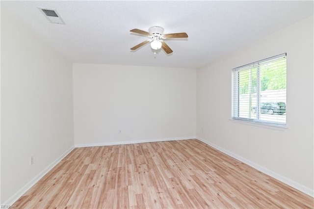 spare room featuring baseboards, visible vents, light wood-style floors, and ceiling fan