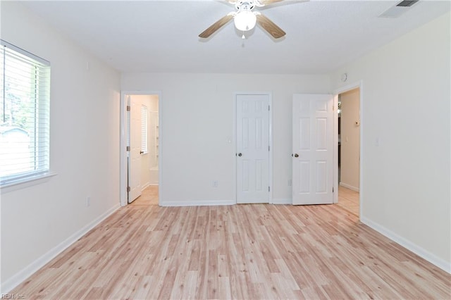 unfurnished bedroom featuring light wood finished floors, baseboards, visible vents, a ceiling fan, and connected bathroom
