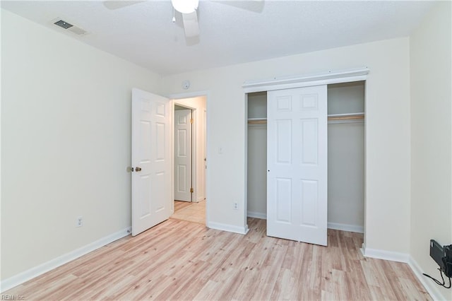 unfurnished bedroom featuring light wood-type flooring, baseboards, visible vents, a ceiling fan, and a closet