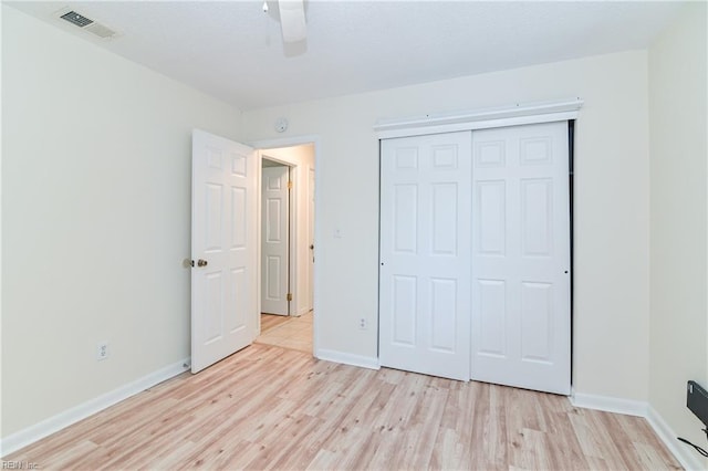 unfurnished bedroom featuring a ceiling fan, a closet, light wood-type flooring, baseboards, and visible vents