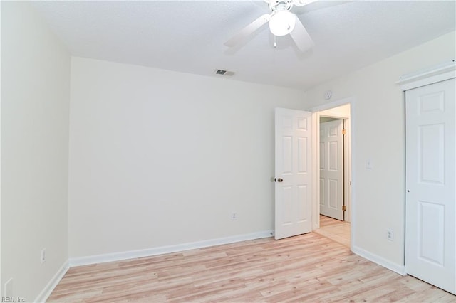 unfurnished bedroom with light wood finished floors, visible vents, a ceiling fan, a closet, and baseboards