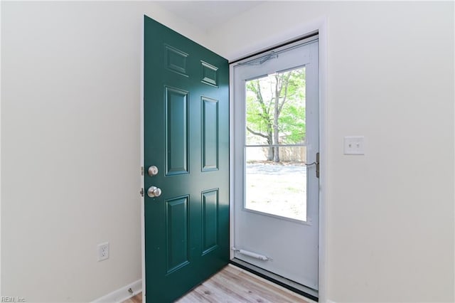 doorway to outside featuring baseboards and light wood finished floors