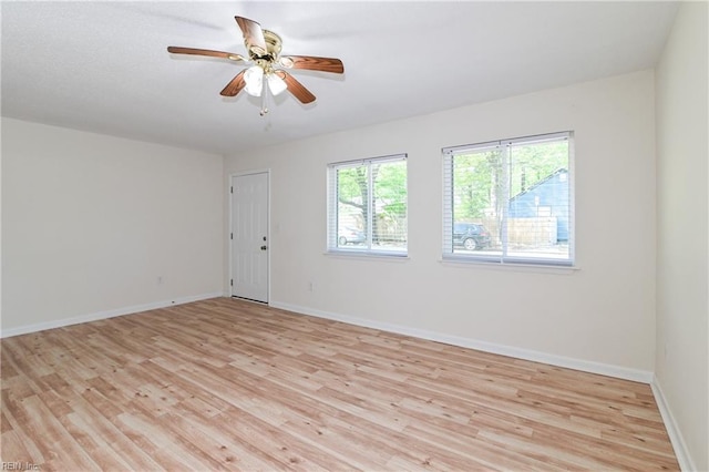 empty room featuring baseboards, a ceiling fan, and light wood-type flooring