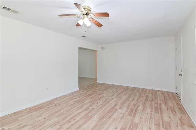empty room featuring baseboards, a ceiling fan, visible vents, and light wood-type flooring