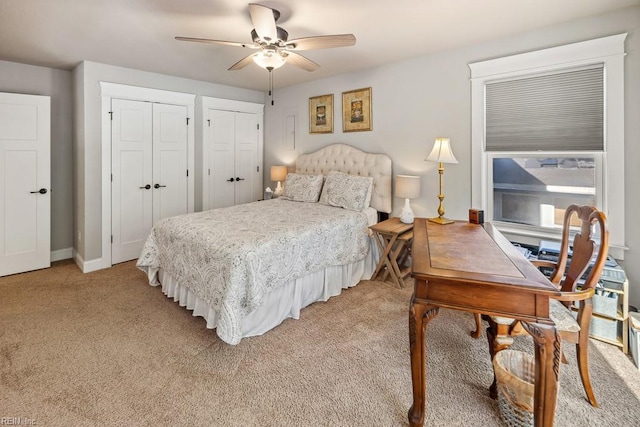 bedroom featuring ceiling fan, multiple closets, baseboards, and light carpet