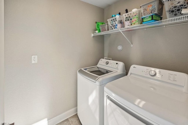 washroom with baseboards, washer and clothes dryer, laundry area, and light tile patterned floors