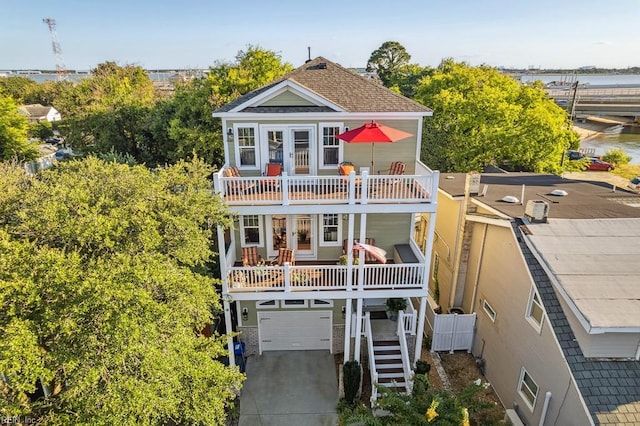 back of property with stairs, a balcony, a water view, an attached garage, and french doors