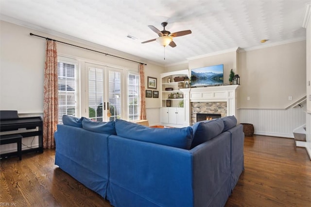 living room featuring french doors, a lit fireplace, wood finished floors, ceiling fan, and ornamental molding