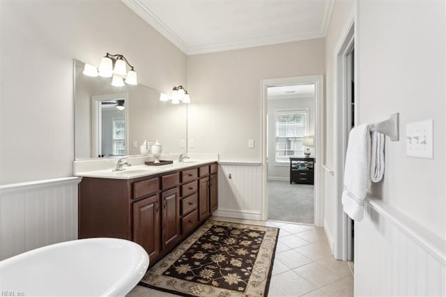 full bath featuring a soaking tub, a wainscoted wall, a sink, double vanity, and crown molding