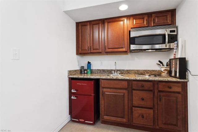 kitchen with a sink, stone countertops, baseboards, appliances with stainless steel finishes, and recessed lighting