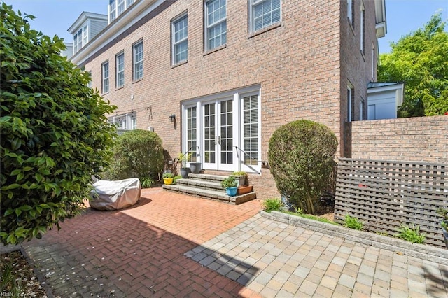 rear view of house featuring brick siding, a patio, entry steps, and french doors
