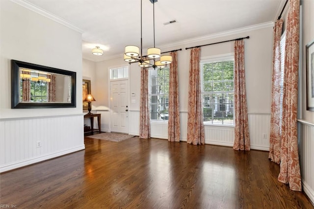 interior space featuring wainscoting, wood finished floors, an inviting chandelier, and ornamental molding
