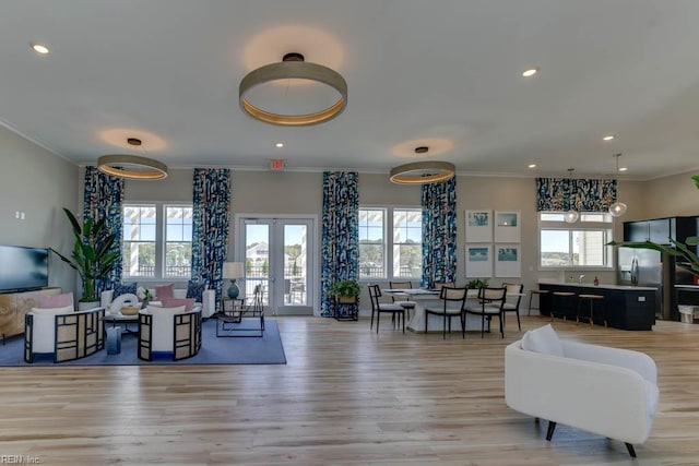 living area with ornamental molding, a healthy amount of sunlight, and light wood-style floors