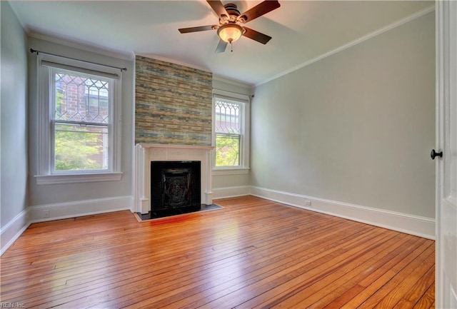 unfurnished living room featuring baseboards, a ceiling fan, a large fireplace, hardwood / wood-style flooring, and ornamental molding