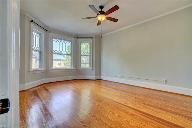 unfurnished room with baseboards, wood finished floors, a wealth of natural light, and crown molding