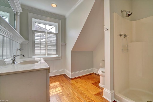 bathroom featuring toilet, wood finished floors, ornamental molding, and a stall shower