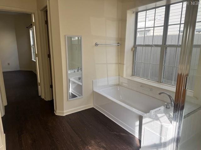 bathroom with baseboards, a garden tub, and wood finished floors