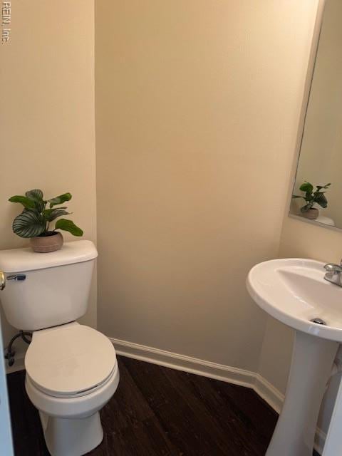bathroom with wood finished floors, toilet, baseboards, and a sink