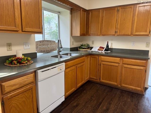 kitchen with white dishwasher, dark countertops, dark wood-style flooring, and a sink