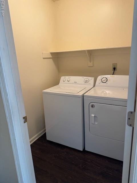clothes washing area featuring separate washer and dryer, baseboards, dark wood-type flooring, and laundry area