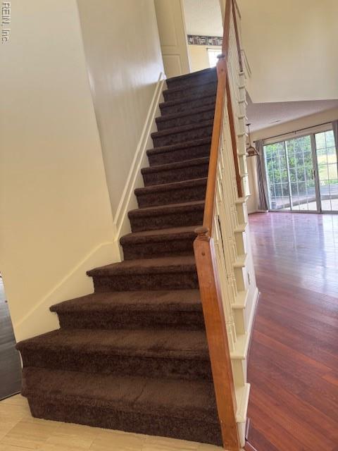 stairs with a towering ceiling and wood finished floors